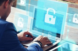 Business, technology, internet and networking concept. Young businessman working on his laptop in the office, select the icon  security on the virtual display.